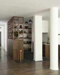 A modern kitchen with an open space design and wooden features, including white cabinets and brown wooden accents.