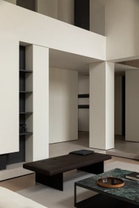Modern living room featuring a black leather ottoman, marble coffee table, and stone and steel elements.