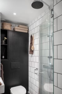 A modern, minimalist bathroom with white tiled walls and black accents.