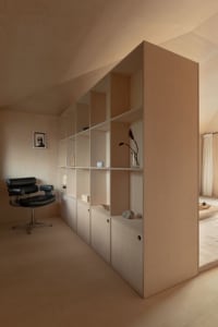 A minimalist office interior with wooden furniture and shelving.