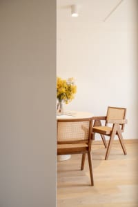 Modern dining room with wooden furniture and a vase of yellow flowers.