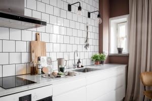 A modern kitchen with white subway tiles, white countertop, and stainless steel appliances.