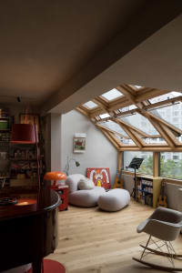 A modern living room featuring a cozy seating area with a skylight and wooden flooring.