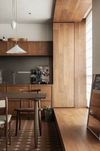 A modern kitchen with minimalist design featuring wooden cabinets and floor.