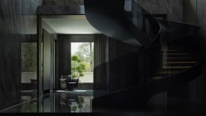 A modern black staircase with glass railings and marble flooring.