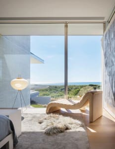 Modern minimalist residential interior featuring large glass window overlooking natural landscape.