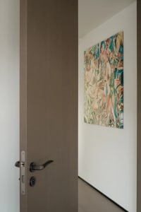 Modern abstract painting with beige, teal, and black patterns installed on a wooden door.