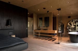Modern bedroom featuring wooden walls, glass partitions, and concrete floor.