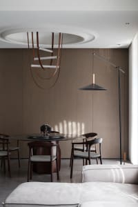 A modern dining room featuring a combination of metal and leather accents on the table, chairs, and lighting fixtures.