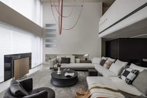 A modern living room with a white sectional sofa, round black coffee table, and large windows.
