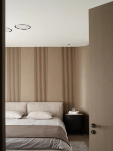 A minimalist bedroom with a bed, pillows, and a nightstand with a glass and books.