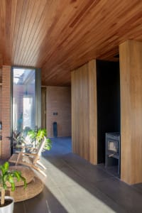 A modern residential interior featuring a wood floor, large windows, and minimalist design.