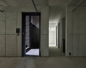 Minimalist concrete interior with a metal elevator and brick wall.
