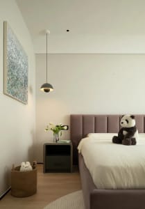 Modern minimalist bedroom with a purple upholstered bed, floating grey pendant light, and minimalistic decor.