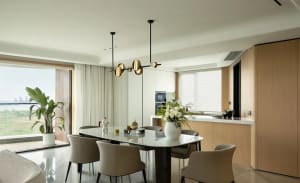 Modern dining room featuring a wooden table with a sleek, minimalist design, surrounded by beige upholstered chairs, and a be