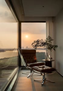 Modern living room featuring a brown leather chair and ottoman with a scenic view of the sunset through large windows.