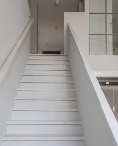 A modern minimalist staircase with white steps and railings.