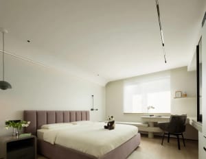 A modern white bedroom with a plush bed, decorative plant, and minimalist design.