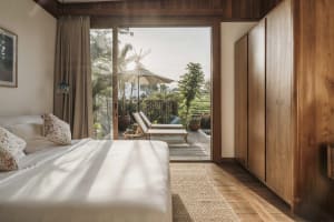Spacious minimalist bedroom with natural light, wood furnishings, and views of the exterior.