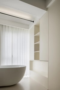 Modern minimalist bathroom featuring ceramic tiles, a freestanding bathtub, and built-in storage