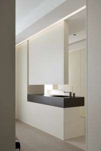 A modern kitchen with minimalist design featuring black concrete countertops and wooden cabinets.