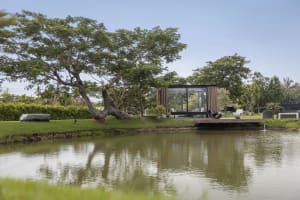 Modern house with glass walls and wood accents on waterfront property.