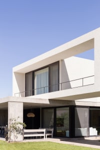 A modern residential building with concrete walls and glass windows, featuring a minimalist design.