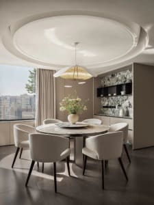 Modern kitchen with marble countertops, light-colored fabric upholstery chairs, and a flower arrangement in the center.
