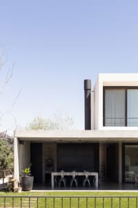 Modern exterior residential space with concrete walls and a black chimney.