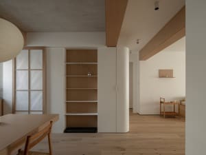 A minimalist apartment featuring a wooden interior with white finishes and natural light.