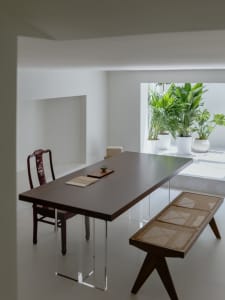 Modern minimalist dining room with a glass table and white walls.