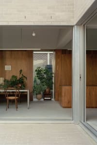 A modern residential living space with wooden walls, glass sliding doors, and concrete flooring.