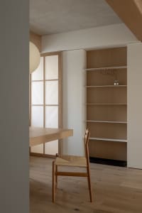A minimalist study with wooden furniture and glass panels.
