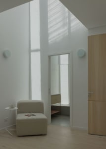 A minimalist living space with wooden panels, featuring a single chair and a small table.