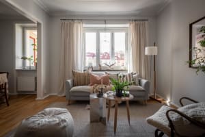 A modern living room featuring fabric curtains, a wood floor, and a potted plant.
