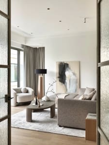 Modern living room with neutral-toned furniture, minimalist decor, and a large abstract painting.
