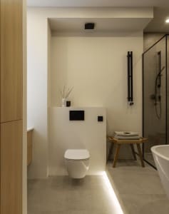 Modern minimalist bathroom with tiled walls, wooden accents, and metal fixtures