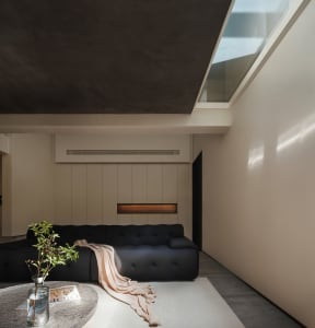 Minimalist living room featuring a concrete sofa and wooden paneling.