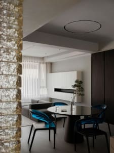 Modern living room featuring transparent blue chairs, glass table, and black accents.
