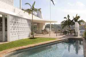 Modern residential exterior with concrete, glass, and greenery
