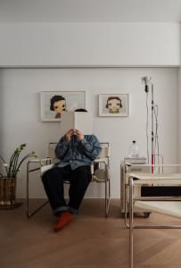 A person sitting in a modern lounge space with metal frame furniture and woven cord sofa.