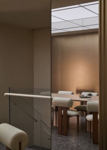 Modern minimalist dining room with wooden furniture and a glass wall.