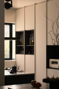Modern kitchen featuring white and black shelves with various bottles and jars.