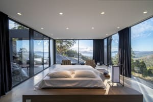 Modern bedroom featuring wood flooring, glass walls, and a view of the landscape.