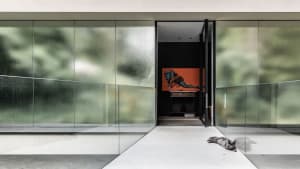 A modern indoor lobby featuring glass walls and concrete flooring.