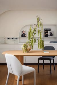 A modern minimalist dining room with a wooden table, marble countertop, and fabric chairs.
