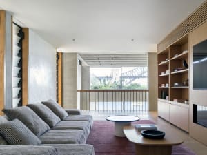A modern living room featuring a concrete floor, large windows, and minimalist furniture.