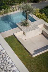Modern poolside concrete furniture featuring a tree planter in a contemporary outdoor lounge area.