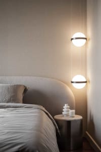 A contemporary bedroom with minimalist design featuring pendant lights and a upholstered bed.