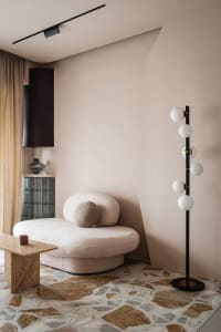 A stylish living room with a plush, rounded sofa and a geometric, terrazzo-patterned floor.